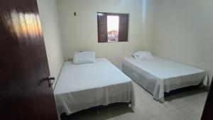2 Betten in einem kleinen Zimmer mit Fenster in der Unterkunft Shambala centro de São Tomé das letras in São Thomé das Letras