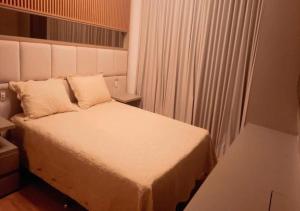 1 dormitorio con cama blanca y ventana en Apartamento luxuoso com infra completa próximo a Praia da Barra da Tijuca, en Río de Janeiro