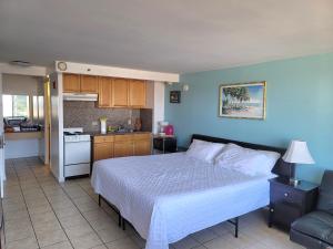 a bedroom with a large bed and a kitchen at Waikiki Condo High Floor Views Beaches Convention Center in Honolulu