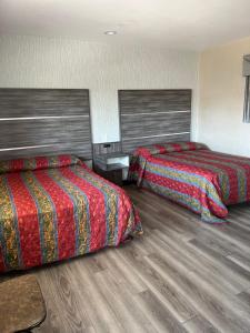 a hotel room with two beds and wooden floors at Keystone Motel in Norwalk