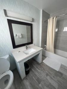 ein Badezimmer mit einem Waschbecken, einem WC und einem Spiegel in der Unterkunft Keystone Motel in Norwalk