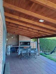 a patio with a wooden roof with a table and chairs at Cabañas del Cerro Mirador in Villa Rumipal