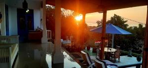 a sun setting on a house with a table and an umbrella at Cantik Villa in Lovina