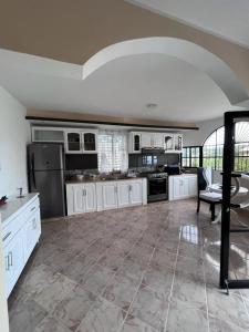 una gran cocina con armarios blancos y una mesa. en Coral Village Family, en Santa Bárbara de Samaná