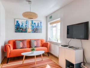 a living room with an orange couch and a tv at Sem Apartments in Reykjavík