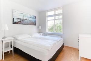 a white bedroom with a large bed and a window at Sem Apartments in Reykjavík