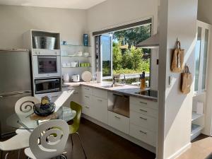 a kitchen with white cabinets and a large window at Lacebark Treetops Cottage: 2 bed/2en-suite option in Havelock North