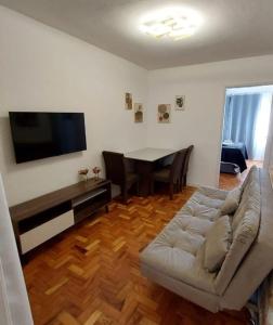 Apartamento encantador perto da Avenida Paulista في ساو باولو: غرفة معيشة مع أريكة وتلفزيون بشاشة مسطحة