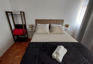 Apartamento encantador perto da Avenida Paulista في ساو باولو: غرفة نوم بسرير كبير مع كرسي احمر