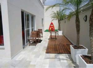a patio with a table and chairs and a palm tree at Apartamento Executivo - No melhor lugar do América in Joinville