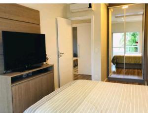 a bedroom with a bed and a flat screen tv at Apartamento Executivo - No melhor lugar do América in Joinville
