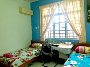 a bedroom with two beds and a window at Homestay Rumah Singgah in Jitra