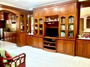 a large room with wooden cabinets and a television at Homestay Rumah Singgah in Jitra