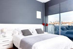 een slaapkamer met een wit bed en een groot raam bij Feelathome Poblenou Beach Apartments in Barcelona