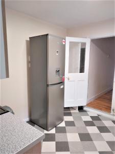 a stainless steel refrigerator in a kitchen with a checkered floor at Cheerful 3 Bedroom Home in Greater London in London