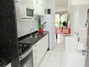 a white kitchen with a sink and a refrigerator at Porto de Galinhas lindo AP 2 Q 2 Banh 40 m da praia in Porto De Galinhas