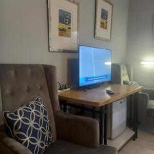 a computer monitor on a wooden desk with two chairs at Mount View Motel in Bulahdelah