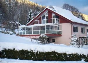 una casa roja con nieve en el suelo en Ferienwohnung Christine, en Bad Wildbad