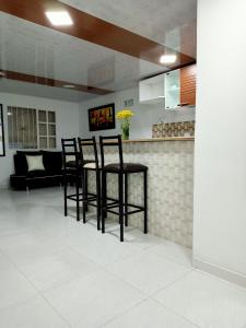 a kitchen with black bar stools in a living room at Hotel Casa Nini in Bogotá