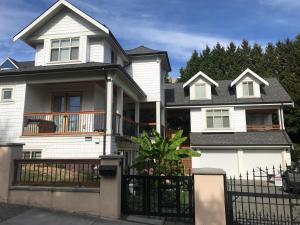 una casa blanca con una valla delante en Holland Villa Vancouver, en New Westminster