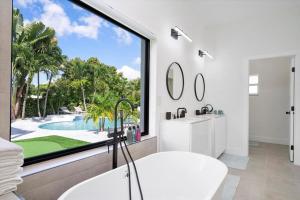 ein Badezimmer mit einem Waschbecken und einem großen Fenster in der Unterkunft VillaLee-Jungle Palm Island white marble pool Area in Miami
