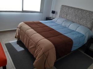 a bedroom with a large bed with a brown and blue blanket at Departamentos Giovanni in Salta +25 photos