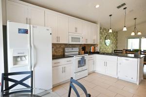 a kitchen with white cabinets and a white refrigerator at Golf getaway fun for family and friends for an Orlando theme park vacation in Davenport