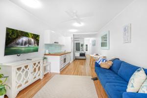 a living room with a blue couch and a tv at Amaroo At Trinity in Trinity Beach