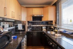 a kitchen with wooden cabinets and black counter tops at 1 Bedroom Flat Close to City with Free Parking Arrangement in London