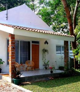 een klein wit huis met een houten veranda bij Villa Kebun Prambanan in Randugunting