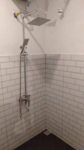 een douche in een wit betegelde badkamer bij Villa Kebun Prambanan in Randugunting