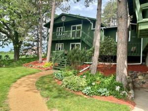 a green house with a porch and trees at Pinehaven of Baraboo in Baraboo