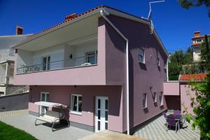 a pink house with a balcony and a table at Holiday house with a parking space Premantura, Medulin - 11631 in Premantura