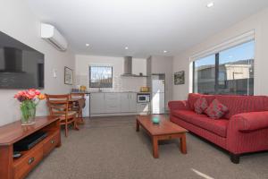 a living room with a red couch and a table at 2 Oaks Cottage Clyde in Clyde