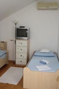 ein Schlafzimmer mit einem Bett und einem TV auf einer Kommode in der Unterkunft Apartments by the sea Sumartin, Brac - 11651 in Sumartin