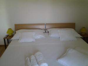 uma grande cama branca com almofadas brancas e 2 candeeiros em Apartments by the sea Sumartin, Brac - 11651 em Sumartin