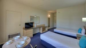 a hotel room with two beds and a desk at Swan Hill Resort in Swan Hill