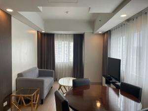 a living room with a table and a couch and a tv at The Residences at BCCT in Manila