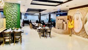 un restaurant avec des tables et des chaises et un mur vert dans l'établissement Daraysh Hotel, à Charjah