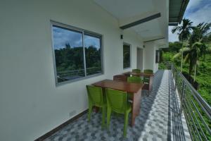 a balcony with a wooden table and green chairs at The Lagoon shade in Port Blair