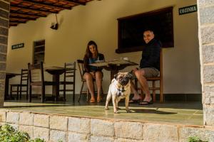 un hombre y una mujer y un perro sentados en un porche en Pousada Tapera, en Penedo