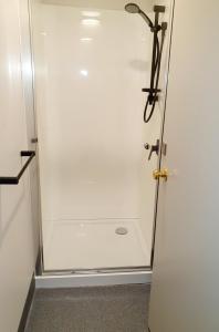 y baño con ducha y puerta de cristal. en Extended Stay City Hostel, en Dunedin