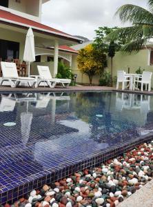 a swimming pool with white chairs and a house at Emma's Guest House and Self-Catering in Au Cap