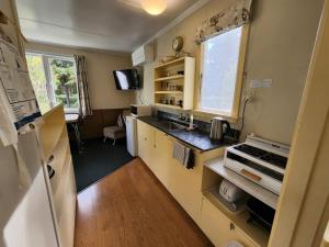 a small kitchen with a sink and a refrigerator at Possum Lodge in Manapouri