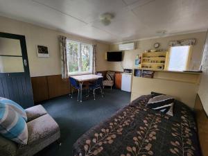 a bedroom with a bed and a table and a kitchen at Possum Lodge in Manapouri