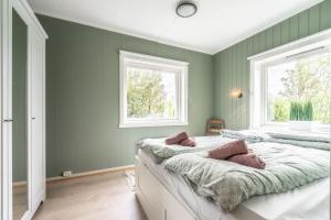 a green bedroom with two beds and two windows at Reine Front View - Mountain & Seaview in Reine