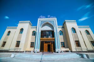 a large building with an arch in front of it at Erkin Palace Hotel in Khiva