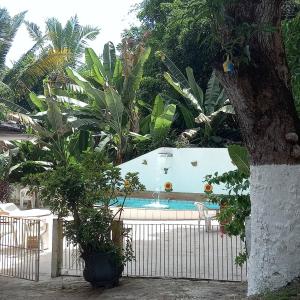 a pool in a garden with a fence and trees at A Pousada da Praia in São Luís