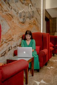 a woman sitting in a red chair with a laptop at Ramada by Wyndham Jaipur North in Jaipur