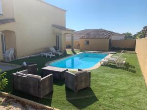 una piscina en un patio con sillas y una casa en Pinet , le calme proche de la mer en Pinet